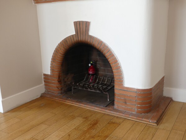 A brick fireplace with a fire extinguisher and a metal grate. - Exceptional apartment with panoramic views, terraces, and private enclosed parking (Grasse)