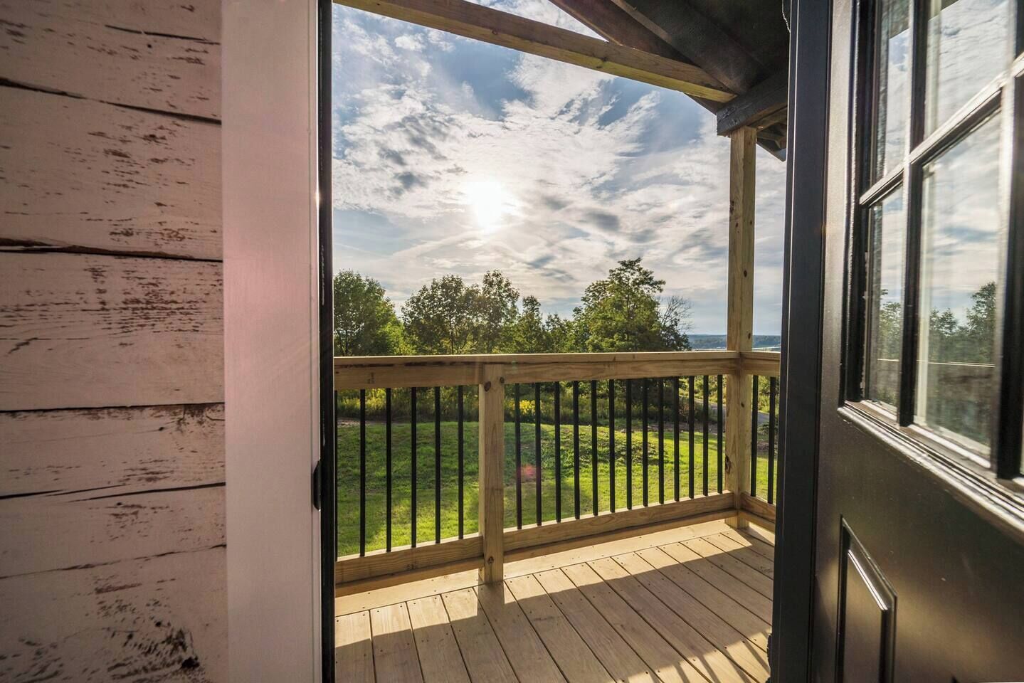 Una terraza de madera con vista a un espacio cubierto de césped y árboles.
