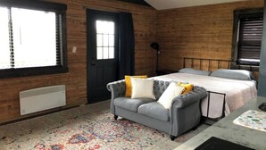 Une pièce avec un lit, un canapé, un radiateur et une fenêtre.