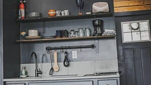 Una cocina con gabinetes grises, una cafetera y diversos utensilios de cocina.