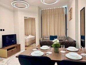 Un comedor moderno con televisor, un sofá y una mesa de comedor preparada para cuatro.