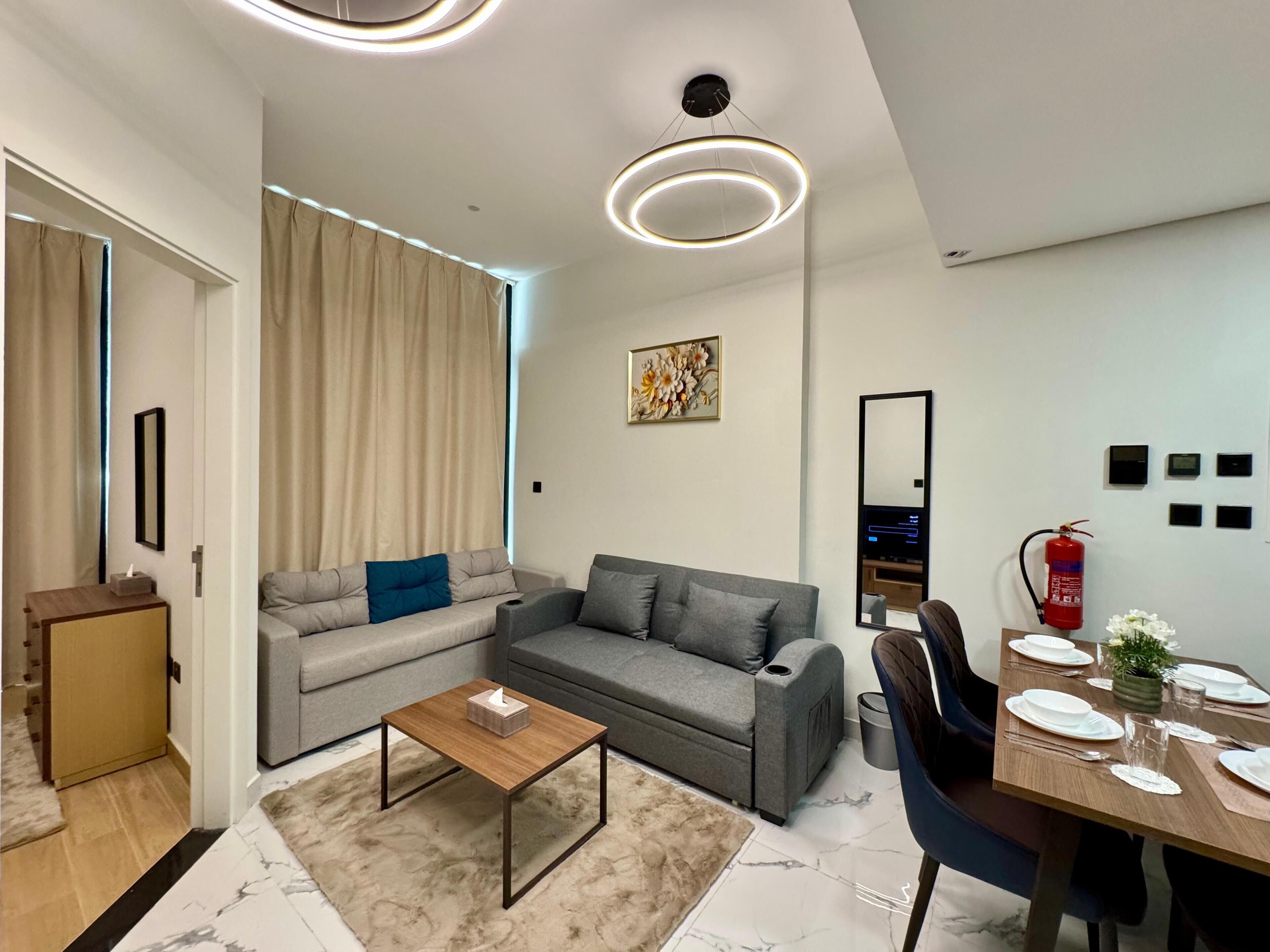 Una sala de estar moderna con un sofá, una mesa de centro y un comedor preparado para cuatro.