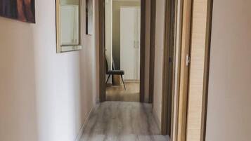 Een hal met een houten vloer, een schilderij aan de wand en een deur aan het einde.