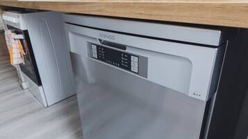 Una cucina moderna con lavastoviglie integrata, un piano di lavoro in legno e un set di bicchieri da vino sopra.