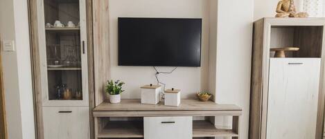 Una sala de estar moderna con un televisor de pantalla plana montado en la pared, muebles de madera y objetos decorativos.