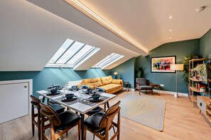 Eine moderne Loftsage mit Essbereich, einer Couch und einem Bücherregal.
