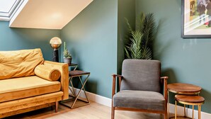 Een gezellige kamer met een bank, een stoel, een tafeltje en een potplant.