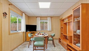Una habitació amb taula de menjador, cadires, televisió i un armari.