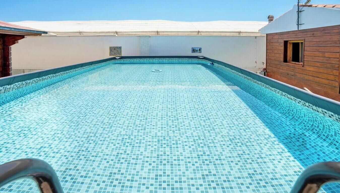Une piscine sur le toit, avec un sol carrelé et un ciel bleu azur au-dessus.