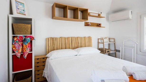 Ein Schlafzimmer mit einem Bett, einem Kleiderschrank, einem Regal mit einem Bild und einer Kleiderstange.