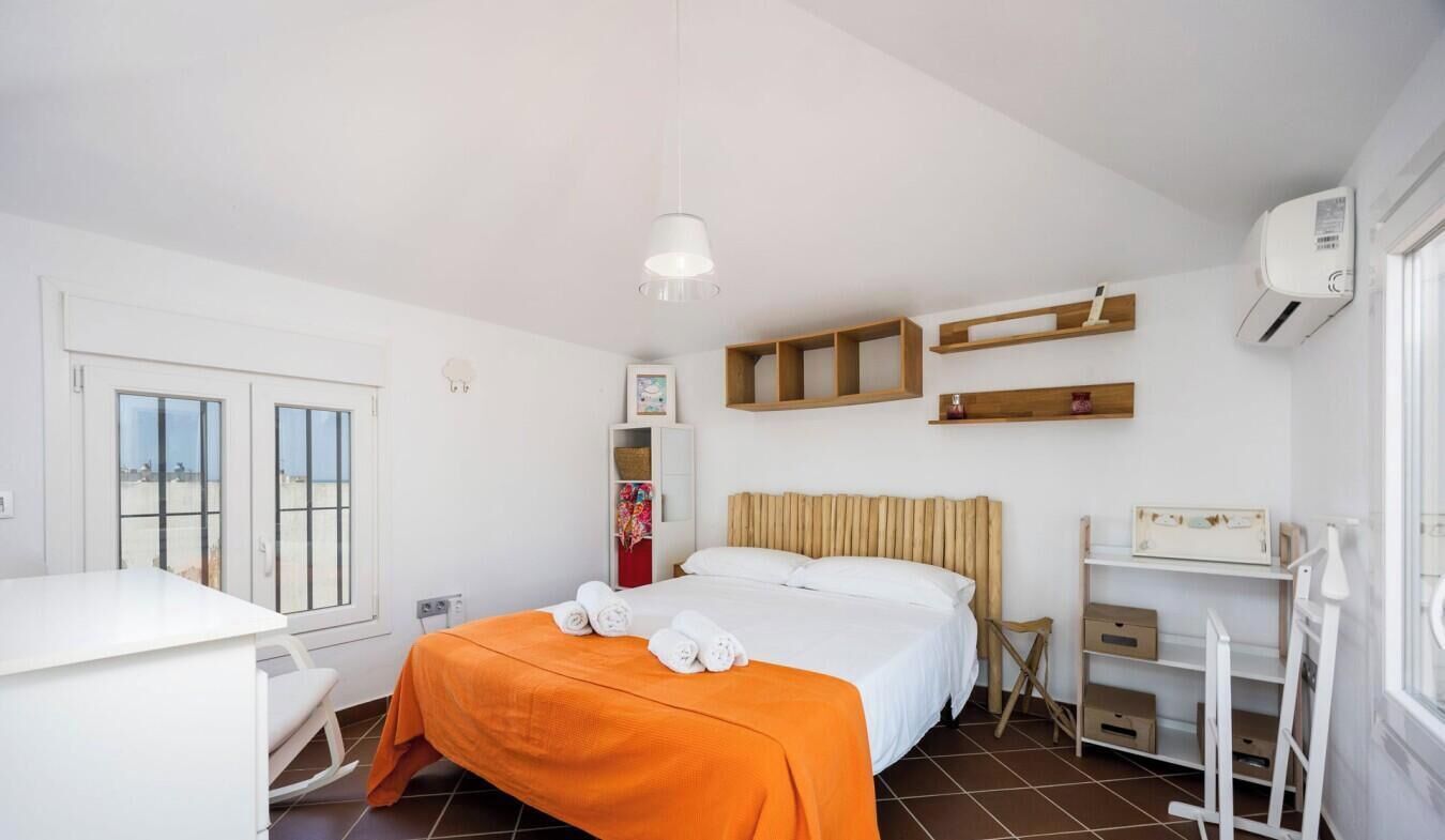 Une chambre d’hôtel équipée d’un lit, d’un bureau, d’une chaise, d’une armoire et d’une fenêtre avec des stores.