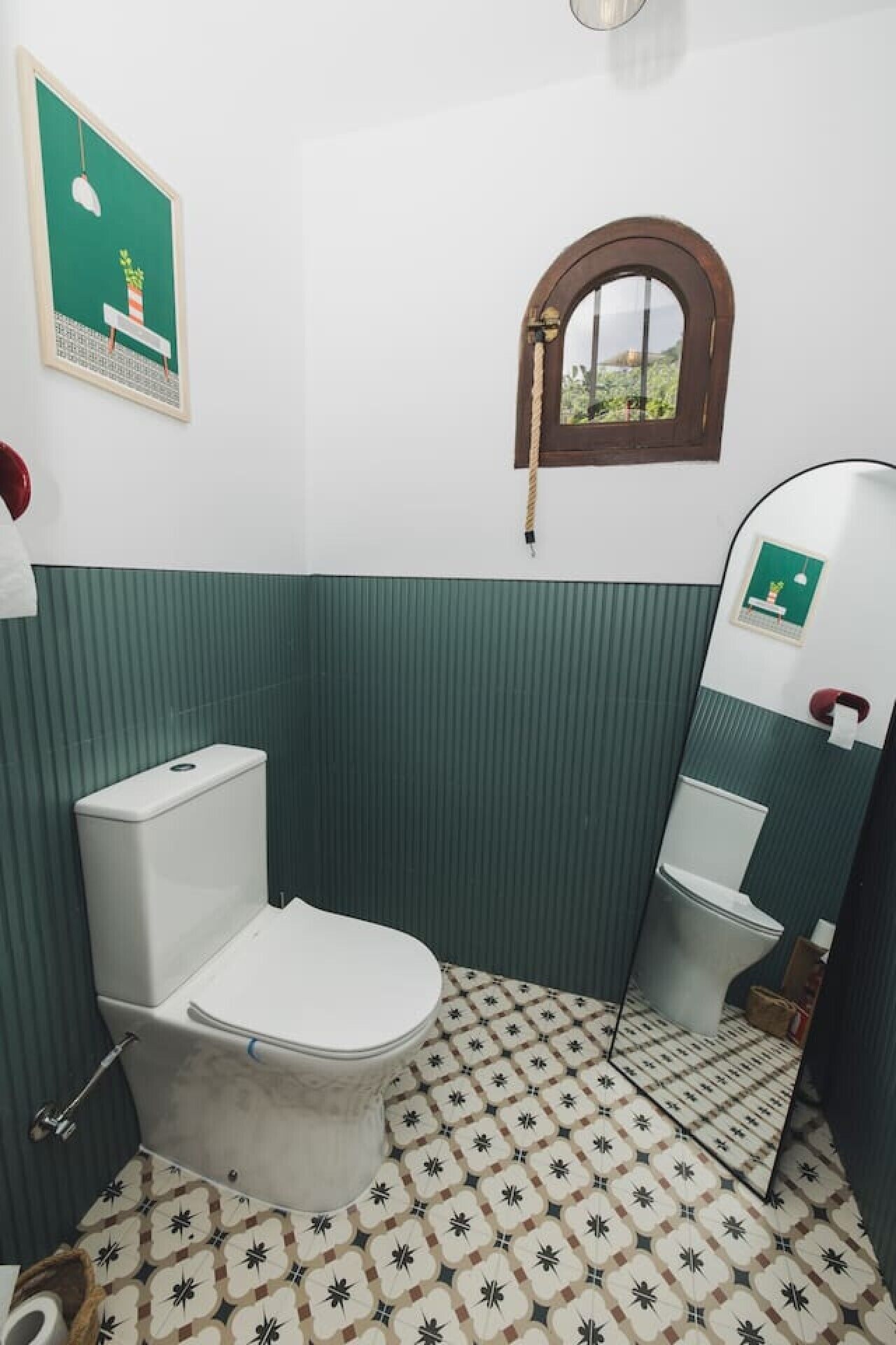 Un bagno con il water, uno specchio, una finestra e una parete verde a righe.