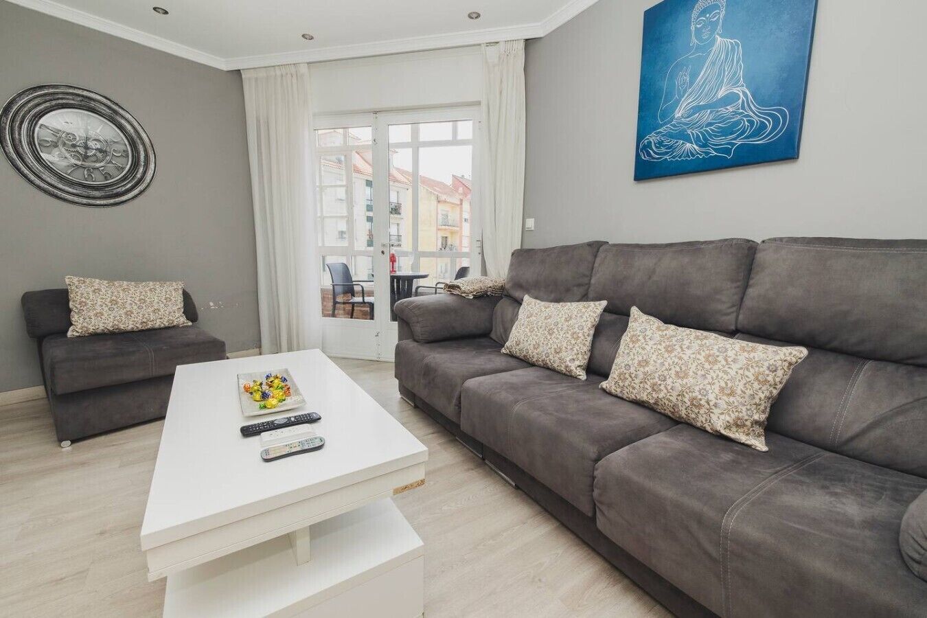 A modern living room with a grey sofa, a white coffee table, and a blue artwork on the wall.