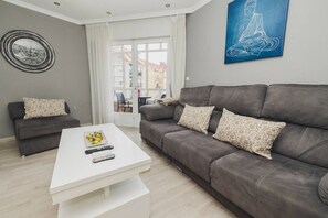 A modern living room with a grey sofa, a white coffee table, and a blue artwork on the wall. - Central Bright Apartment · Beach & Rías Baixas (Vilagarcía de Arousa)