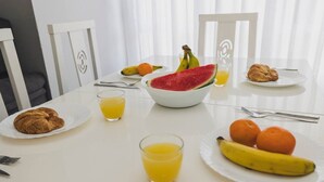 Ein Esstisch mit Speisen, einer Wassermelone und Gläsern Orangensaft.