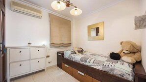 A bedroom with a bed, a dresser, a window with curtains, a mirror, and a teddy bear. - Large Beachfront Apartment - Cádiz (Cádiz)