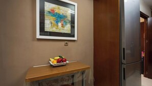 A kitchen with a wooden table, a fruit bowl, a refrigerator, and a framed artwork on the wall. - Large Beachfront Apartment - Cádiz (Cádiz)