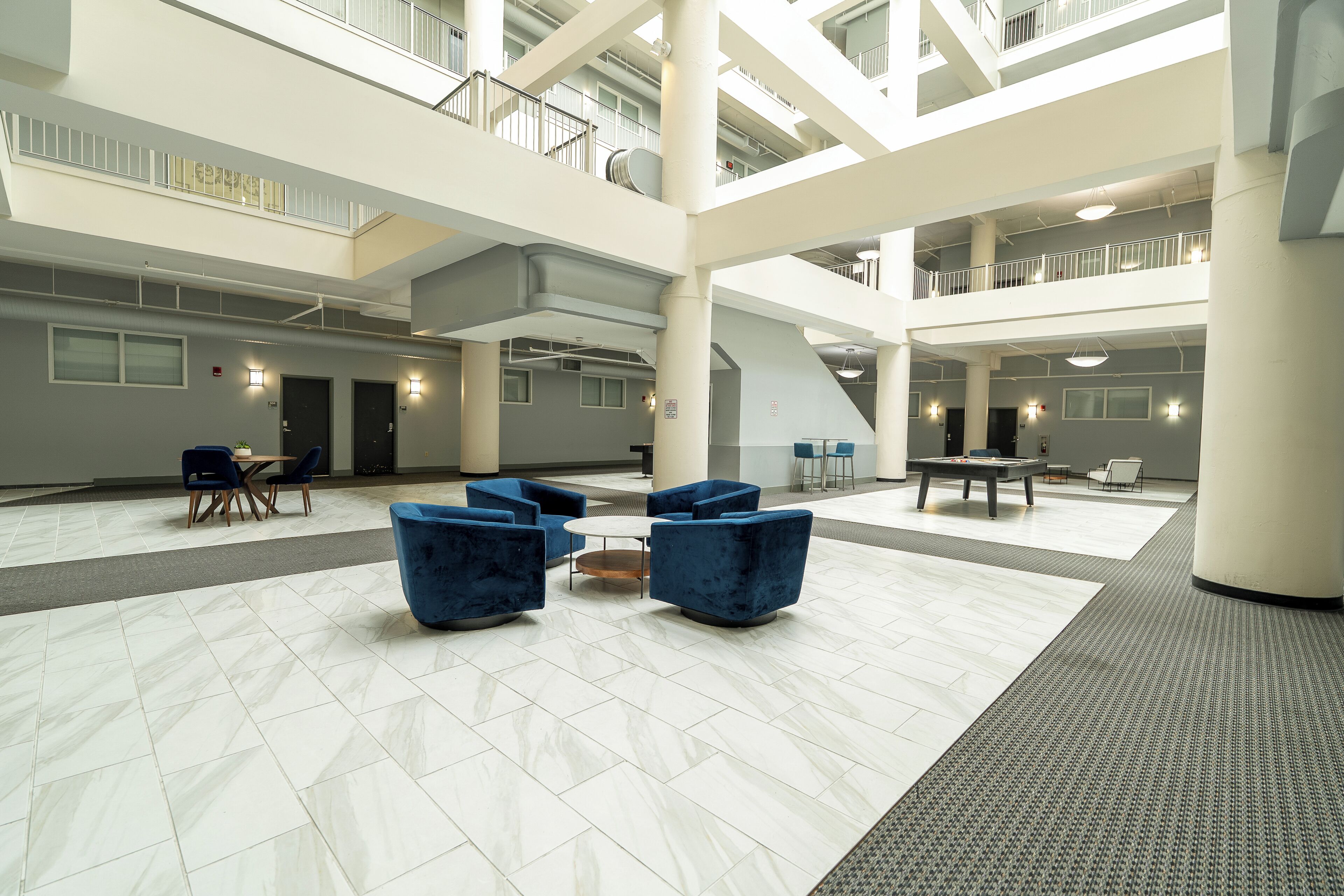 A spacious lobby with a high ceiling, multiple levels, and a pool table.