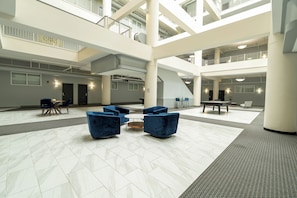 A spacious lobby with a high ceiling, multiple levels, and a pool table.