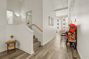 A hallway with a staircase, a small table with a plant, and a colorful wall decoration. - New Downtown Indy Group Stay +4BR+Sleeps 14 (Indianapolis)