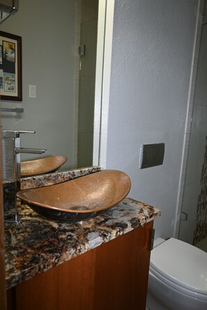 A bathroom with a granite countertop, a wooden vanity, a copper sink, a mirror, and a toilet. - 2 min walk to gondola! (Vail)
