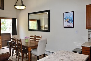 A dining area with a wooden table, chairs, a vase with flowers, a large mirror, and a framed picture on the wall. - 2 min walk to gondola! (Vail)