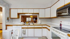 A compact kitchen with white cabinets, a microwave, a dishwasher, and a sink. - Bethany Beach - 830 Westwood Ave Unit C (Bethany Beach)