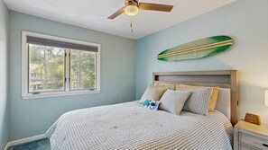 A bedroom with a bed, a ceiling fan, a window, and a surfboard decoration. - Bethany Beach - 830 Westwood Ave Unit C (Bethany Beach)
