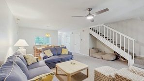 A modern living room with a sofa, coffee table, and a staircase. - Bethany Beach - 830 Westwood Ave Unit C (Bethany Beach)