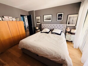 Ein Schlafzimmer mit einem großen Bett, einem Kleiderschrank, einem Nachttisch mit Lampe und einem Bücherregal.