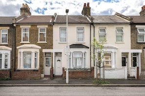 A row of terraced houses with front doors, windows, and a street lamp. - Rose’s Home: Charming 3-Bed House in Stratford (London)