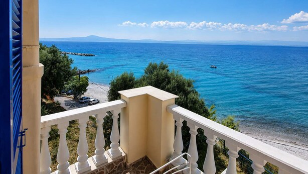 Ein Balkon mit Blick auf das Meer, einen klaren Himmel und ferne Berge.