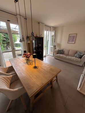 A dining area with a wooden table, chairs, pendant lights, and a vase with flowers. - Casa Mare - Panoramic View of the Ligurian Sea (San Lorenzo al Mare)