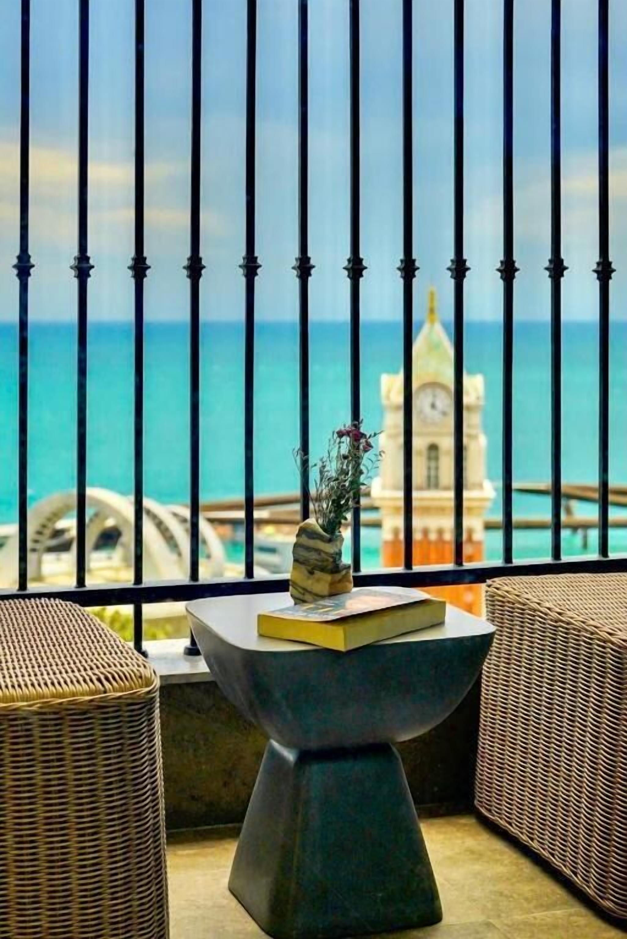 A balcony with a view of the ocean and a clock tower.