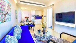 A modern living room with a blue sofa, a round coffee table, and a flat-screen TV.