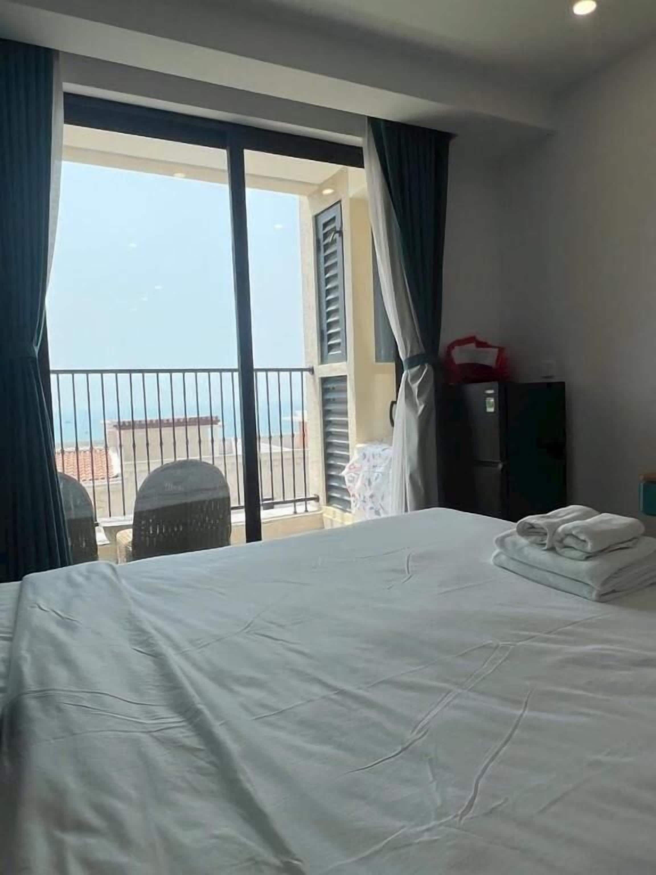 Een hotelkamer met een bed, een balkon en een raam met gordijnen.