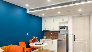 A compact kitchen with white cabinets, a microwave, and a refrigerator.