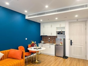 A compact kitchen with white cabinets, a microwave, and a refrigerator.