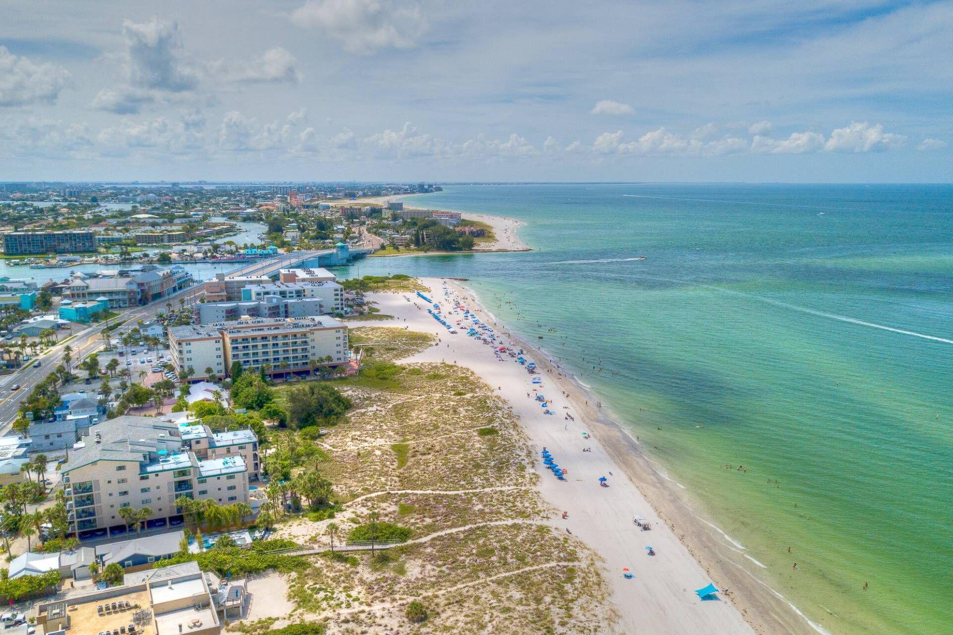 Un hotel frente al mar con varias construcciones, una playa y aguas turquesas cristalinas.