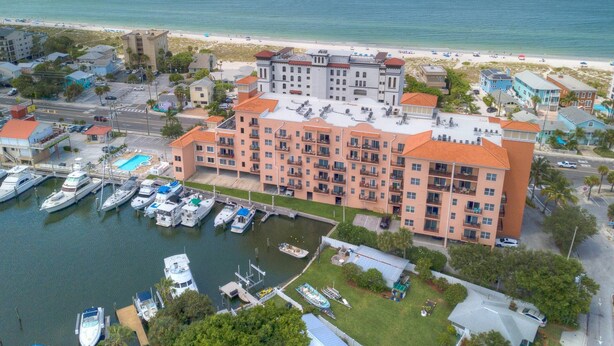A multi-story hotel with balconies, a marina with boats, and a beach in the background. - Private Elevator, Spectacular Pool & Marina Views, Steps to Madeira Beach & John's Pass Village (Madeira Beach)