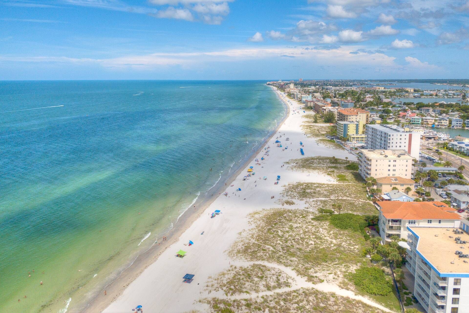 A coastal cityscape with a beach, buildings, and a clear sky.