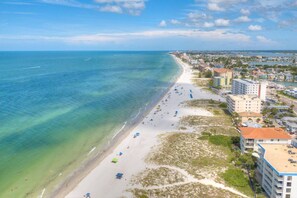 A coastal cityscape with a beach, buildings, and a clear sky. - Private Elevator, Spectacular Pool & Marina Views, Steps to Madeira Beach & John's Pass Village (Madeira Beach)