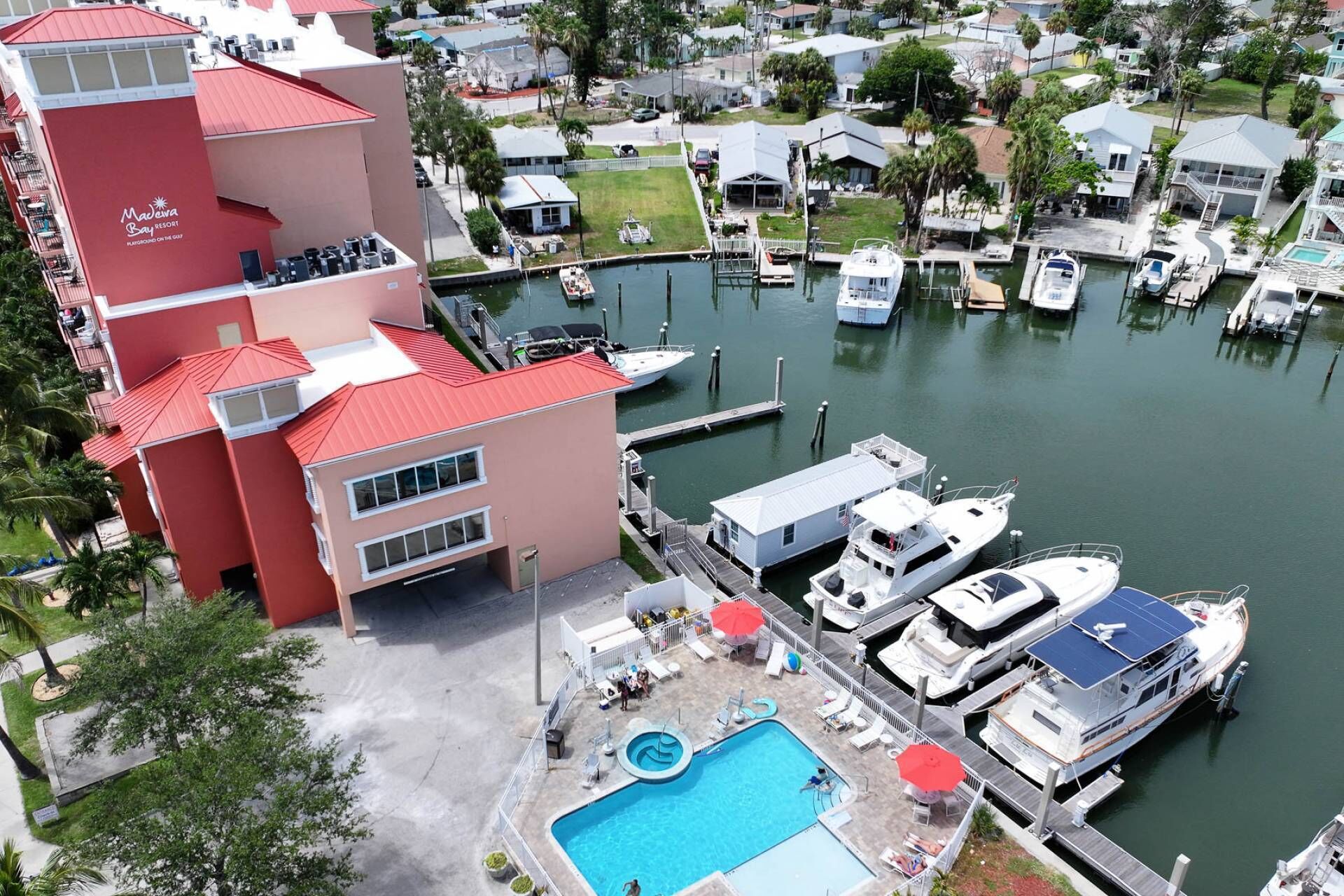 Un puerto deportivo con barcos amarrados, una piscina y un edificio con techo rojo.