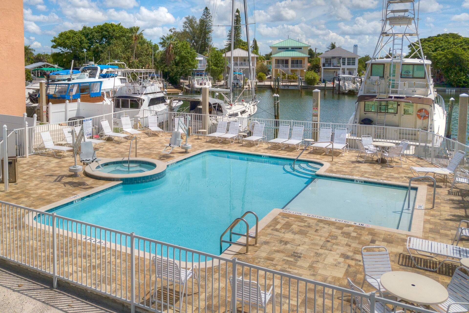 A swimming pool with a shallow water area, surrounded by lounge chairs and a deck area.