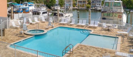 A swimming pool with a shallow water area, surrounded by lounge chairs and a deck area.
