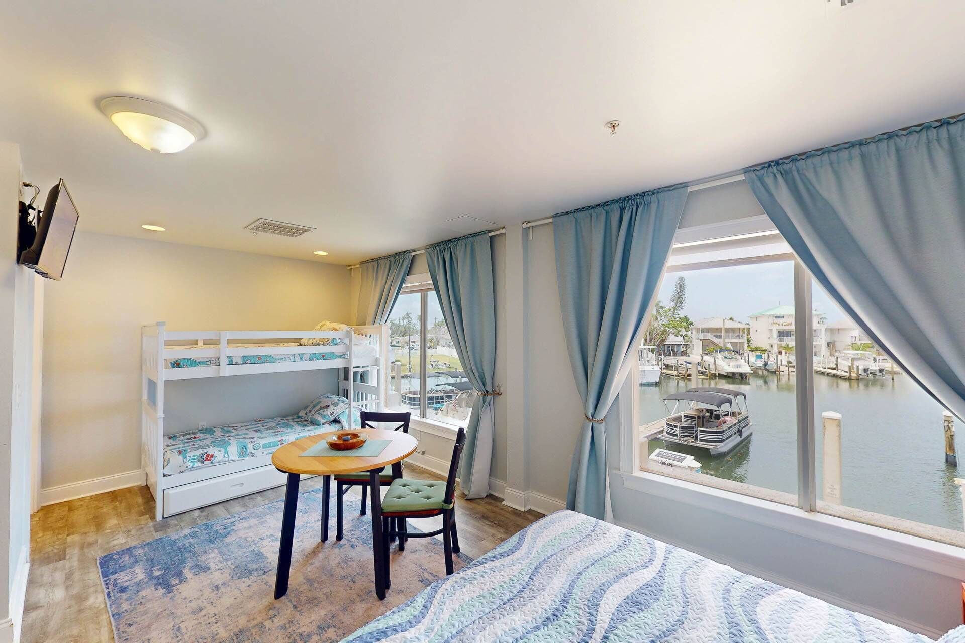 Ein Zimmer mit einem Etagenbett, einem Esstisch mit Stühlen und Blick auf eine Marina.