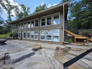 A two-story building with a stone patio and a staircase leading to a deck. - Wonderful 5-bedroom Lake House on Lake Martin (Equality)