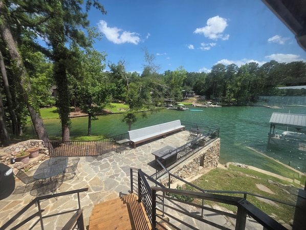 A deck with outdoor furniture overlooking a lake, stone flooring, and a stone wall. - Wonderful 5-bedroom Lake House on Lake Martin (Equality)