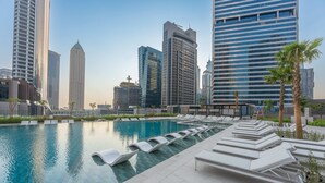 Ein Dachpool mit Liegestühlen und einer Skyline im Hintergrund.