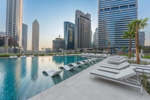A rooftop swimming pool with lounge chairs and a city skyline in the background. - Free Housekeeping Visits During Your Stay - Stayshort - Studio in Business Bay Sleeps 2 With Burj Views (Dubai)